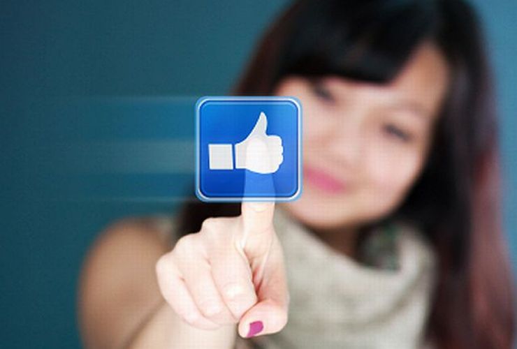Uma mulher toca no símbolo de LIKE do Facebook ilustra nosso artigo sobre: Como criar uma marca digital.
